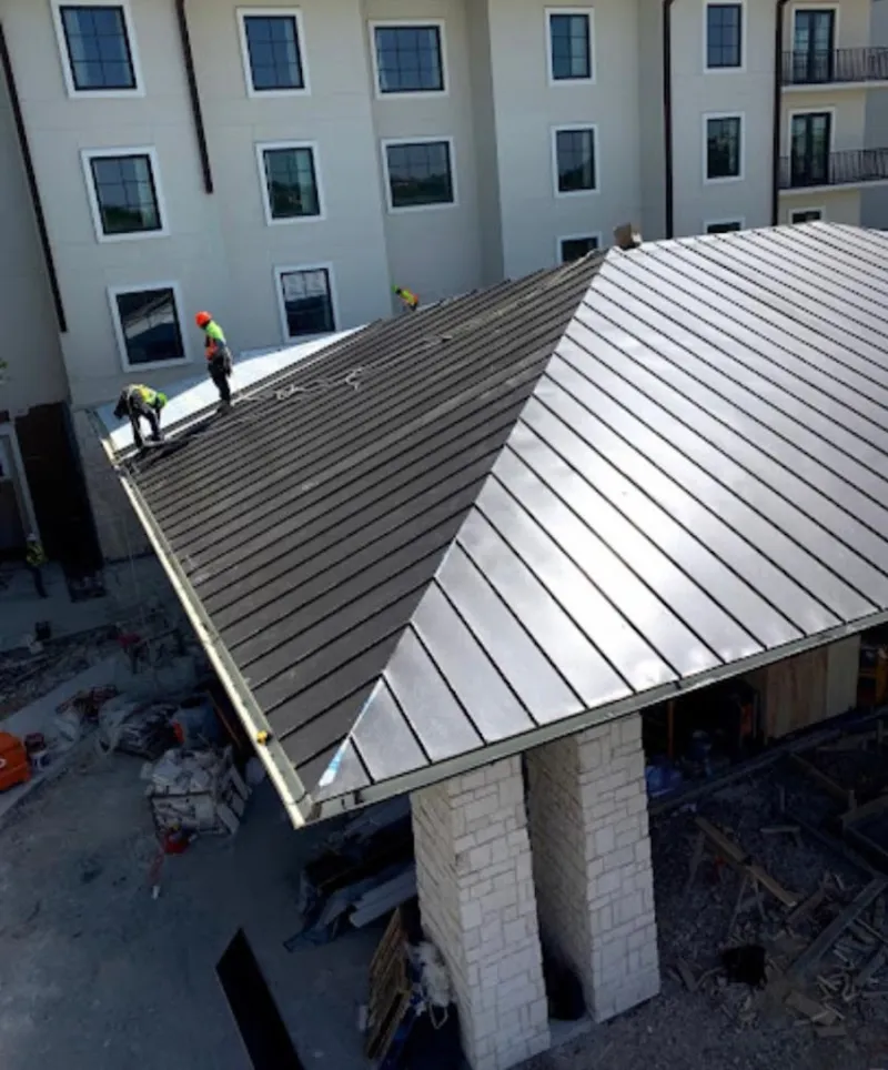 Crew installing standing seam metal roof panels on a commercial project in Southchase